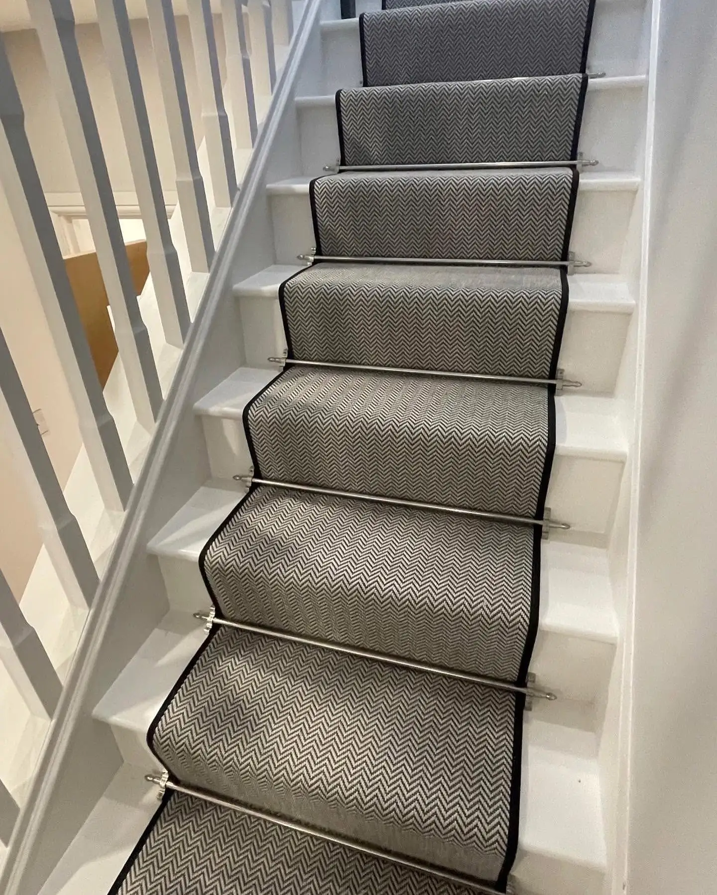Alternative Carpets Stair Runner in Chevron Pattern with Matching Black Carpet Tape Runner and Stairrods on a White Wood Staircase Made and Fitted by Floormaster Yorkshire