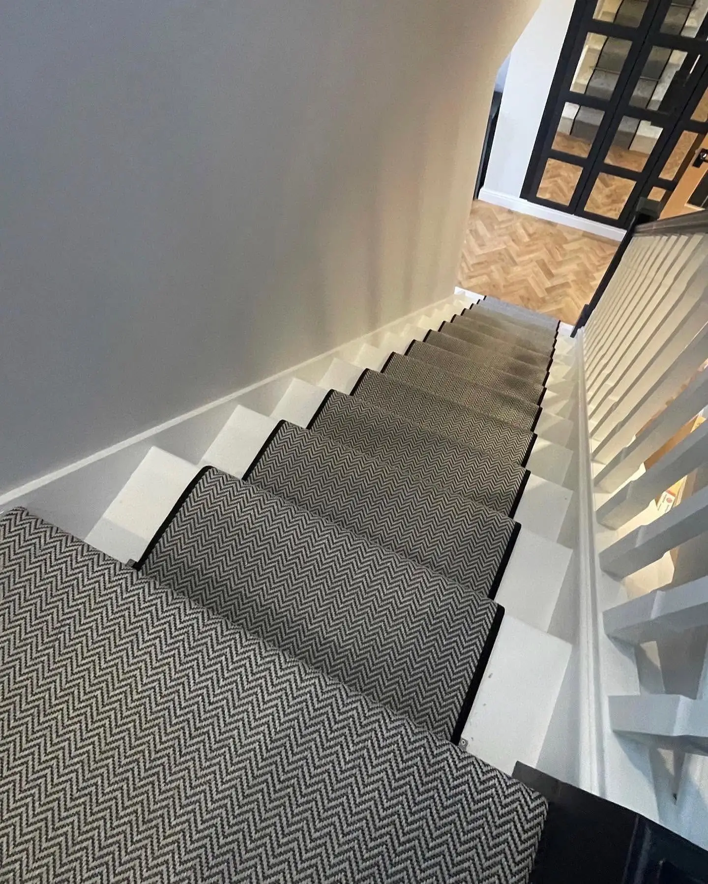Carpet Stair Runner in Herringbone Chevron Pattern with Matching Black Carpet Tape Runner on a White Wood Staircase with Herringbone Hall Floor Made and Fitted by Floormaster Yorkshire